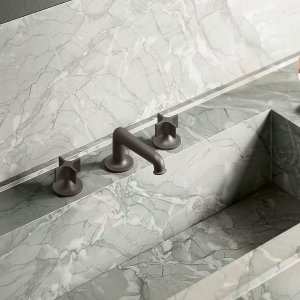 Baterie monocomandă Flora cromată pe un lavoar din piatră deschisă la culoare